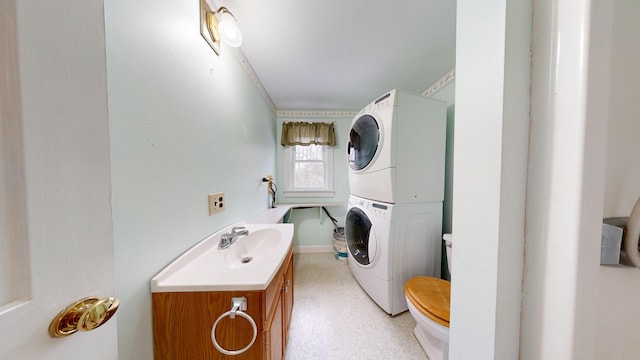 washroom featuring sink, stacked washing maching and dryer, and crown molding