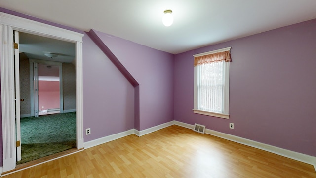 empty room featuring hardwood / wood-style flooring and a baseboard heating unit