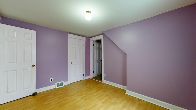 unfurnished bedroom featuring hardwood / wood-style floors and vaulted ceiling