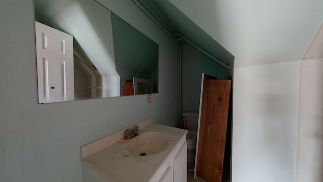 bathroom with lofted ceiling, vanity, and toilet