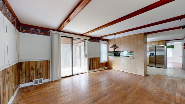 unfurnished living room with light hardwood / wood-style floors and beamed ceiling