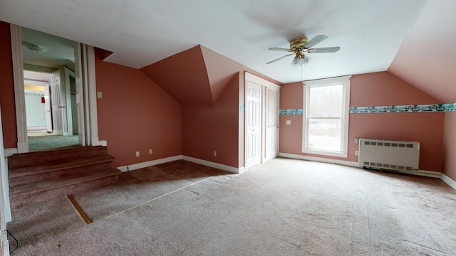 additional living space with ceiling fan, vaulted ceiling, radiator heating unit, and carpet