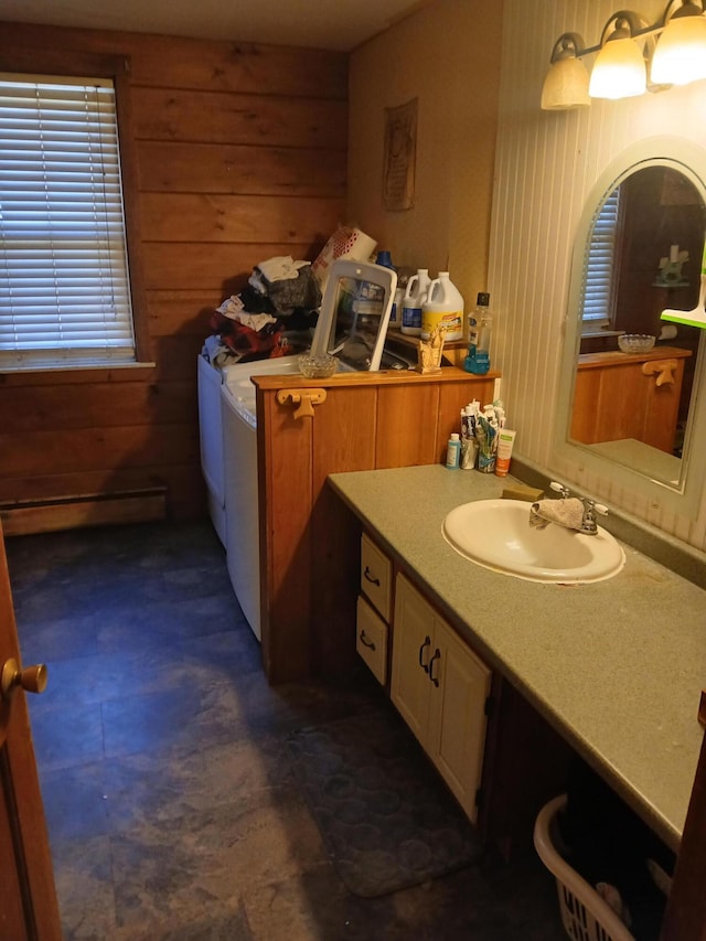 bathroom featuring baseboard heating, wooden walls, and sink