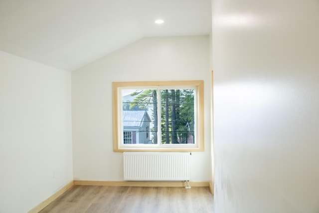 284 Flanders Pond Rd, Sullivan, ME 04664 - empty room with radiator heating unit, light wood-type flooring, vaulted ceiling, and recessed lighting