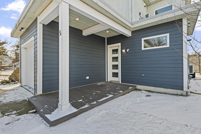 snow covered property entrance with a garage