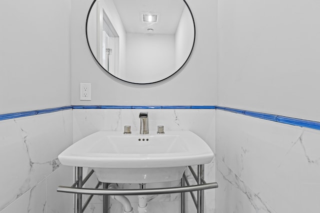 bathroom featuring sink and tile walls