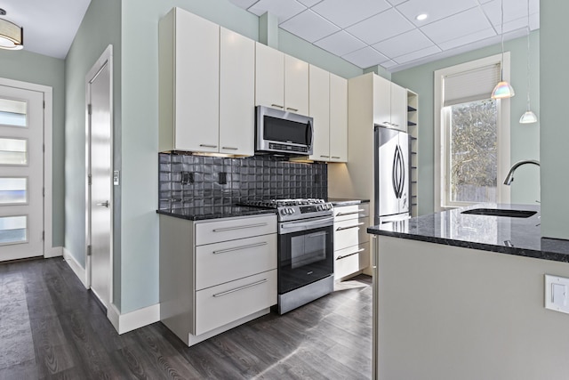 kitchen featuring decorative light fixtures, stainless steel appliances, tasteful backsplash, white cabinets, and sink