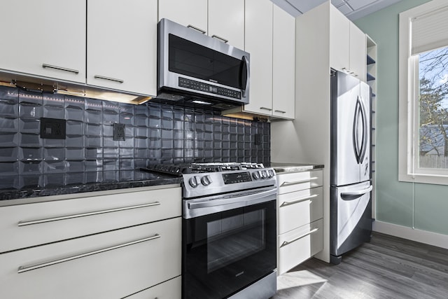 kitchen featuring dark stone counters, appliances with stainless steel finishes, decorative backsplash, and white cabinetry