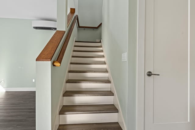 stairway with a wall mounted AC and wood-type flooring