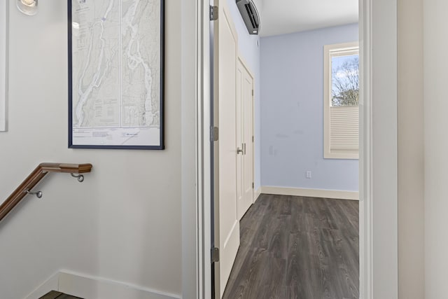 hallway with a wall unit AC and dark hardwood / wood-style flooring