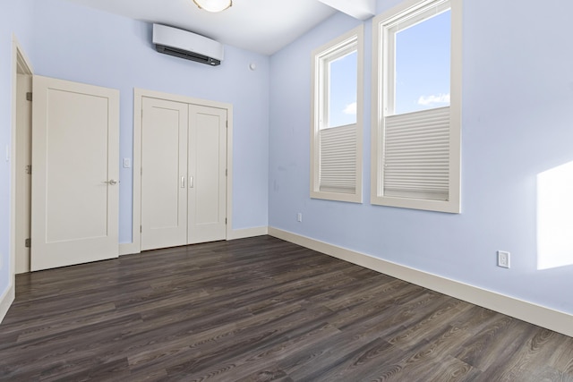 unfurnished bedroom with a closet, a wall mounted air conditioner, and dark hardwood / wood-style floors