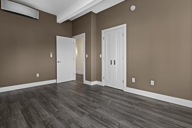 unfurnished room with dark wood-type flooring, beam ceiling, and a wall mounted air conditioner