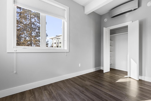 unfurnished bedroom with beamed ceiling, dark hardwood / wood-style flooring, and a wall mounted air conditioner