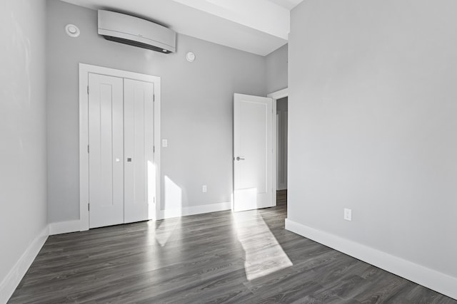 unfurnished bedroom featuring a closet, a wall mounted air conditioner, and dark hardwood / wood-style flooring