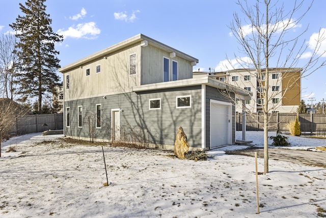 snow covered house featuring a garage