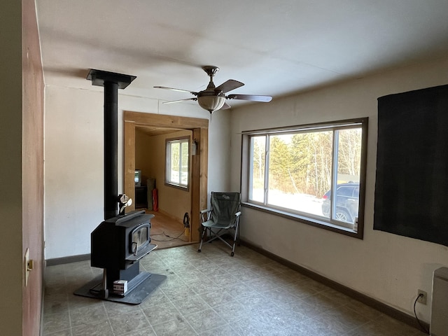 unfurnished living room with ceiling fan and a wood stove