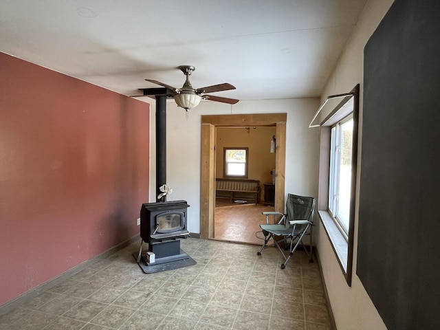 living area featuring ceiling fan and a wood stove