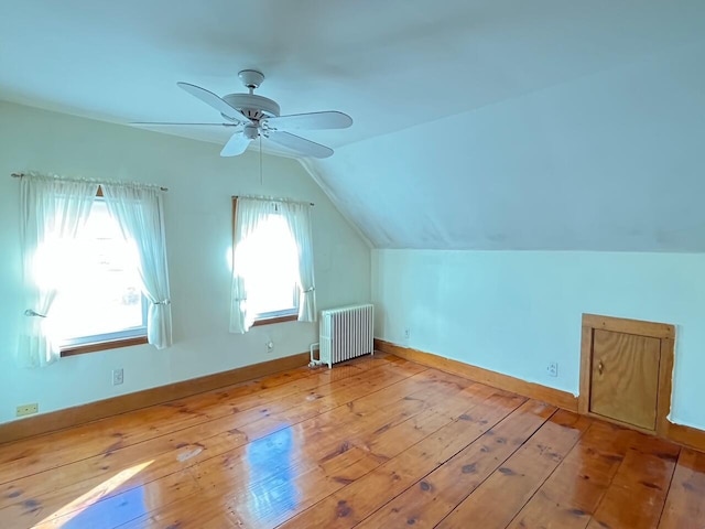 additional living space with radiator, ceiling fan, a wealth of natural light, and light hardwood / wood-style floors