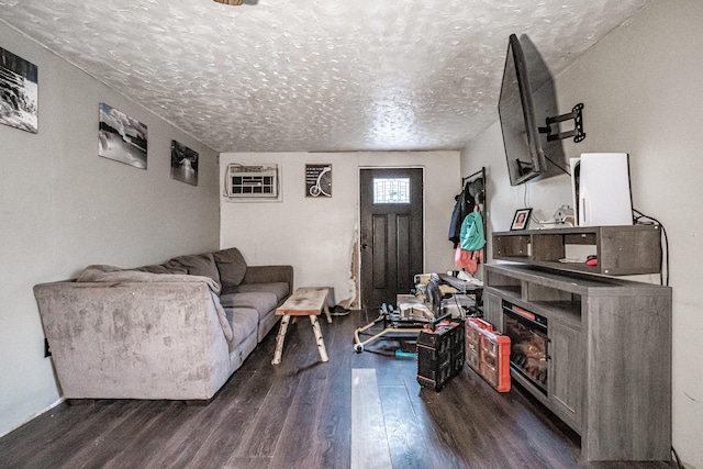 living room featuring dark hardwood / wood-style flooring, a textured ceiling, and a wall mounted AC