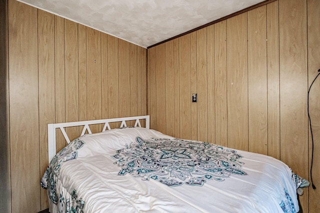 bedroom featuring wood walls and a textured ceiling