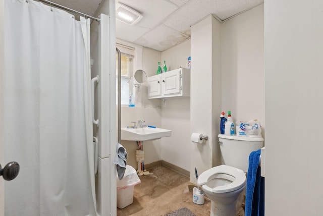 bathroom with a drop ceiling, sink, and toilet