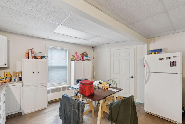 dining area featuring radiator heating unit and a paneled ceiling