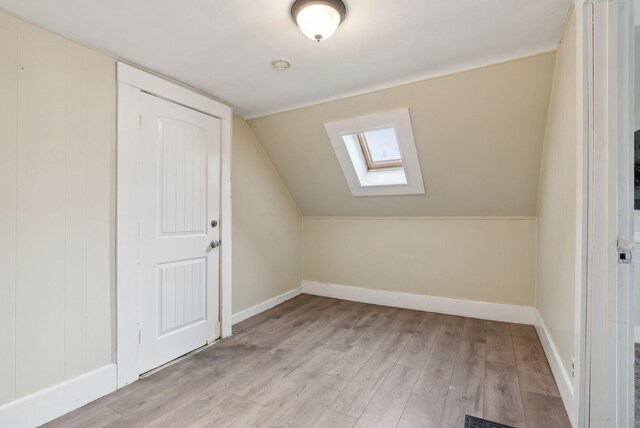 bonus room with vaulted ceiling with skylight and light hardwood / wood-style floors