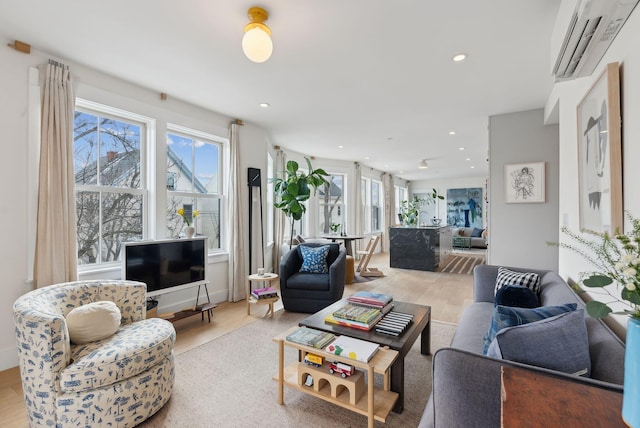 living room with an AC wall unit and light hardwood / wood-style flooring