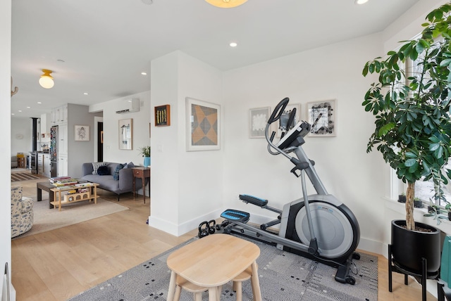 workout area with light hardwood / wood-style floors and a wall mounted air conditioner