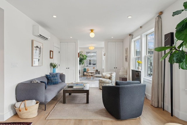 living room with a wall mounted AC and light hardwood / wood-style floors