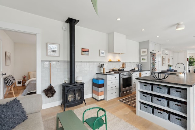 kitchen with premium range hood, light hardwood / wood-style flooring, white cabinetry, appliances with stainless steel finishes, and sink