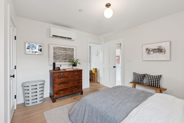 bedroom with a wall mounted AC and light hardwood / wood-style floors