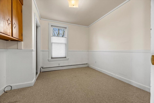 carpeted empty room featuring a baseboard heating unit and crown molding