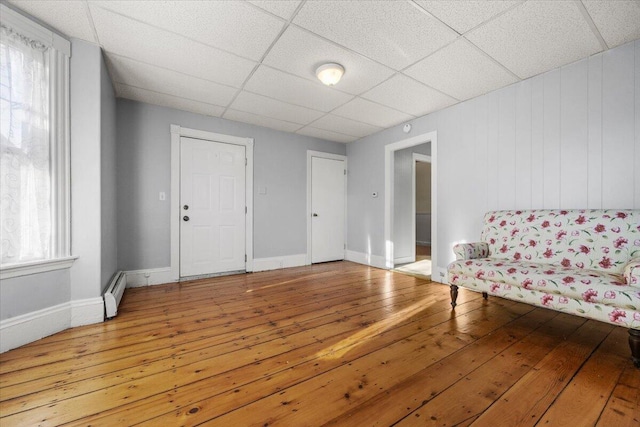 living area featuring a paneled ceiling, a baseboard radiator, hardwood / wood-style floors, and a healthy amount of sunlight