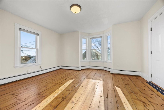 interior space with a wealth of natural light, baseboard heating, and light hardwood / wood-style flooring