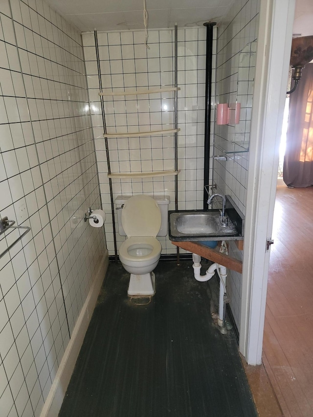 bathroom featuring wood-type flooring, tile walls, and toilet