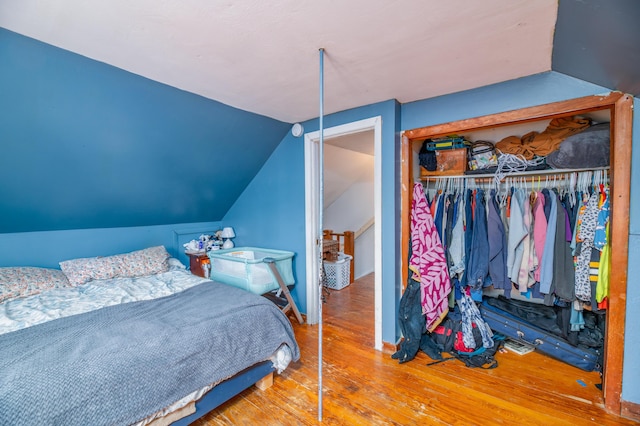 bedroom featuring vaulted ceiling, a closet, and hardwood / wood-style flooring