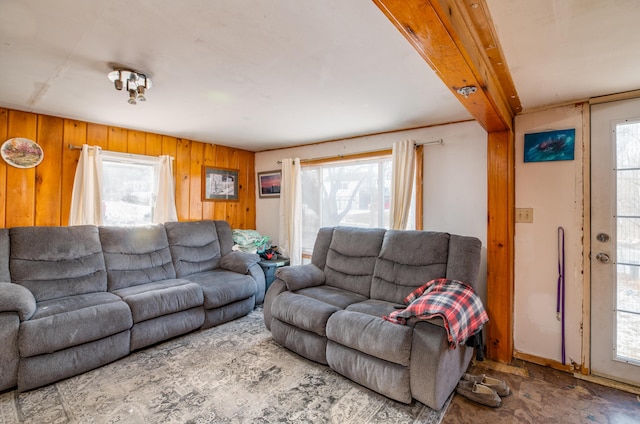 living room with beamed ceiling and wood walls