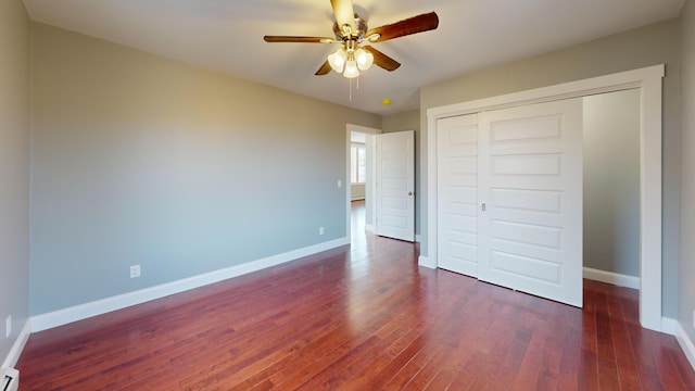 unfurnished bedroom with ceiling fan, dark hardwood / wood-style flooring, a baseboard radiator, and a closet