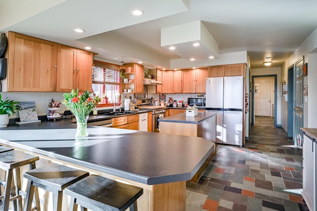 kitchen with sink, a center island, a breakfast bar, and appliances with stainless steel finishes