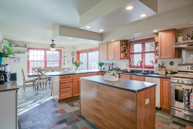 kitchen with stainless steel stove, a healthy amount of sunlight, a center island, ceiling fan, and sink