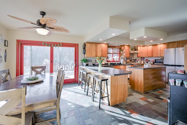 kitchen with sink, a center island, ceiling fan, a breakfast bar area, and appliances with stainless steel finishes