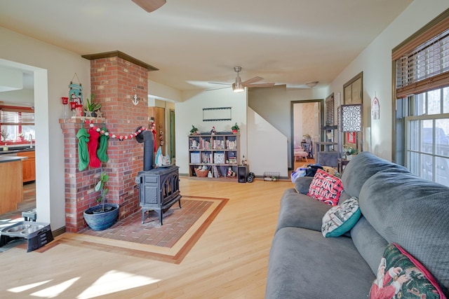 living room featuring ceiling fan, a wood stove, and hardwood / wood-style floors