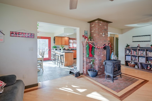 living room featuring ceiling fan, a wood stove, and wood-type flooring