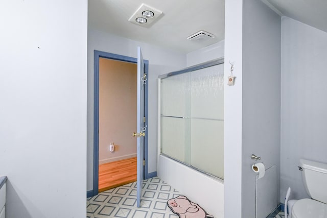 bathroom featuring combined bath / shower with glass door and toilet