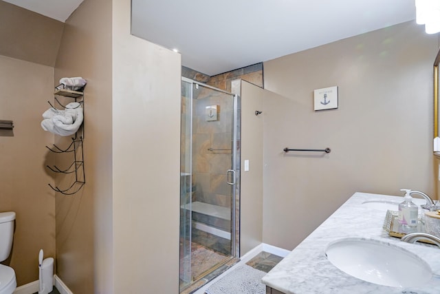 bathroom featuring a shower with door, vanity, and toilet