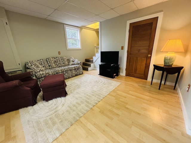 living room with a drop ceiling and light wood-type flooring