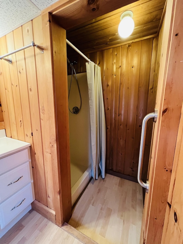 bathroom with vanity, a shower with curtain, wood-type flooring, wooden walls, and wooden ceiling