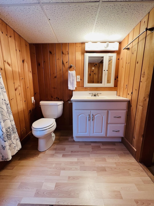 bathroom featuring vanity, a drop ceiling, and wooden walls