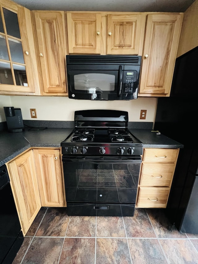 kitchen featuring light brown cabinetry, dark tile patterned flooring, and black appliances